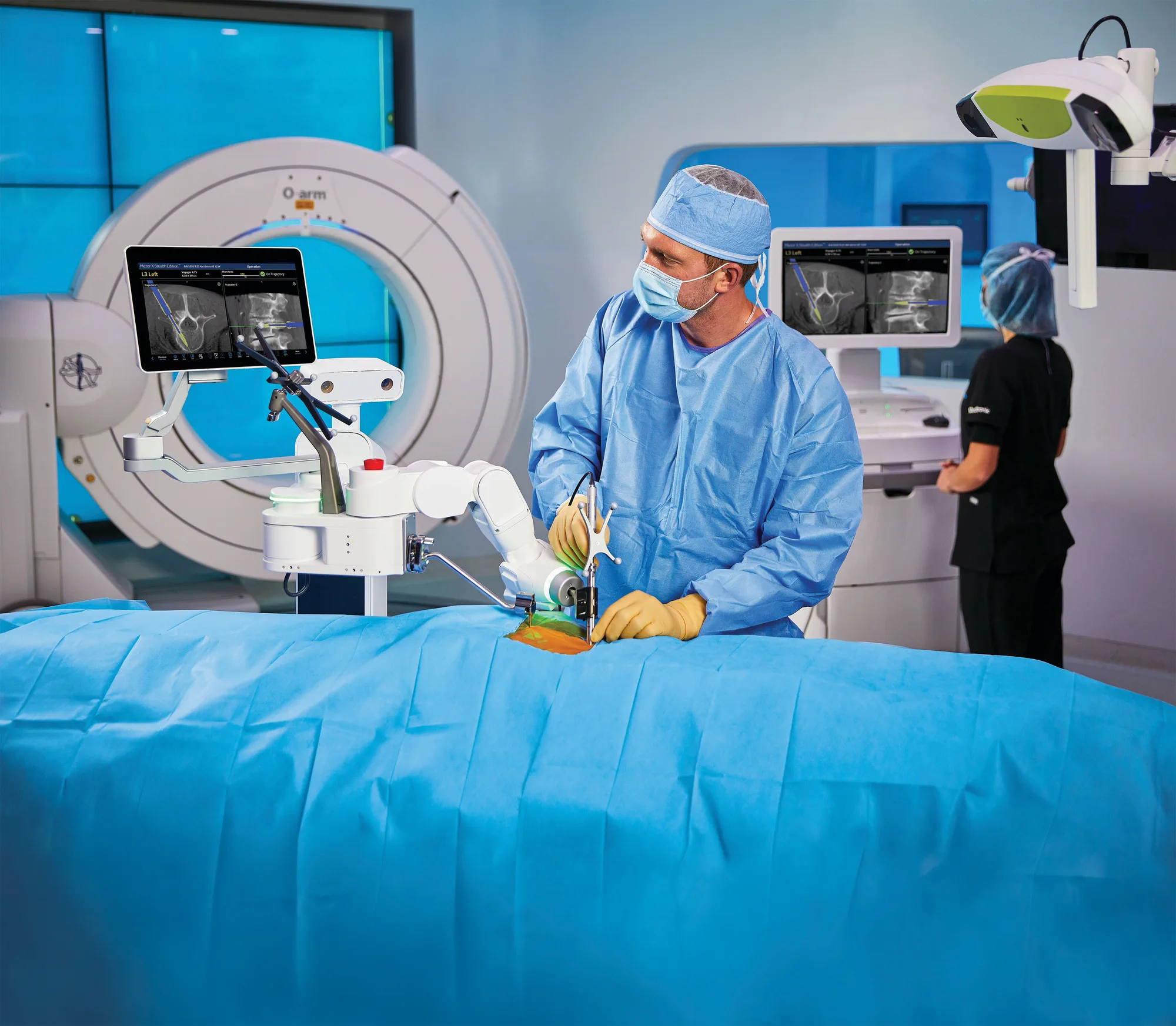 A surgeon operating with navigation and the Medtronic Mazor robot, the O-arm scanner behind and two screens showing the instrument on the CT scan