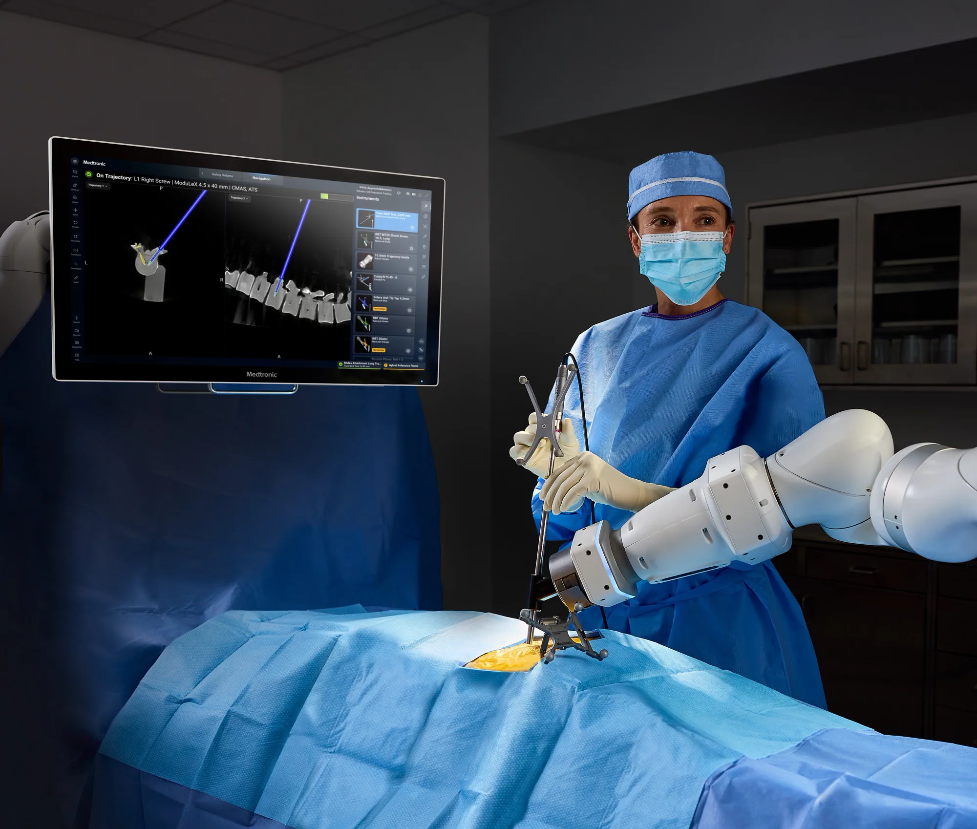A surgeon working with a Medtronic robotic arm, which holds the instrument guide over the spine while the screen beside it shows the planned screw path