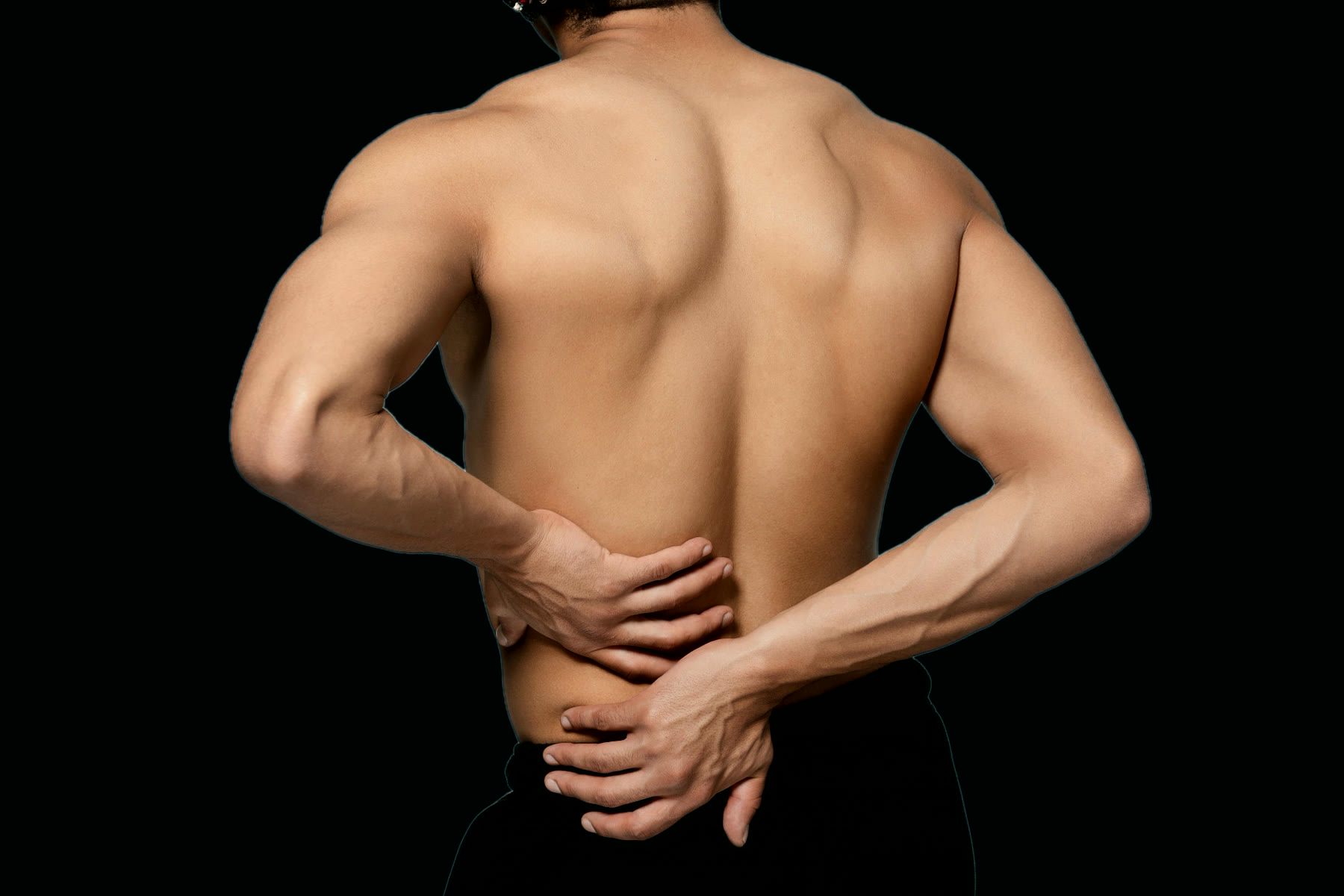 A man seen from behind, both hands pressed to his lower back